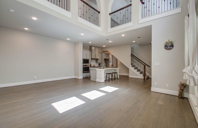 unfurnished living room with a high ceiling and wood-type flooring