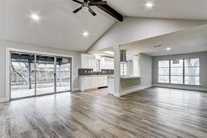 unfurnished living room featuring hardwood / wood-style flooring, vaulted ceiling with beams, and ceiling fan