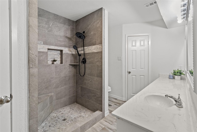 bathroom with vanity, toilet, and a tile shower