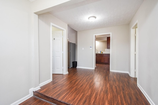 hall with dark hardwood / wood-style flooring, sink, and a textured ceiling