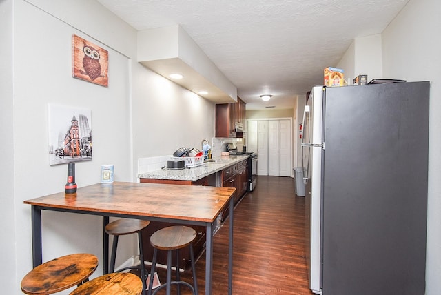 kitchen featuring appliances with stainless steel finishes, dark hardwood / wood-style floors, sink, decorative backsplash, and a textured ceiling