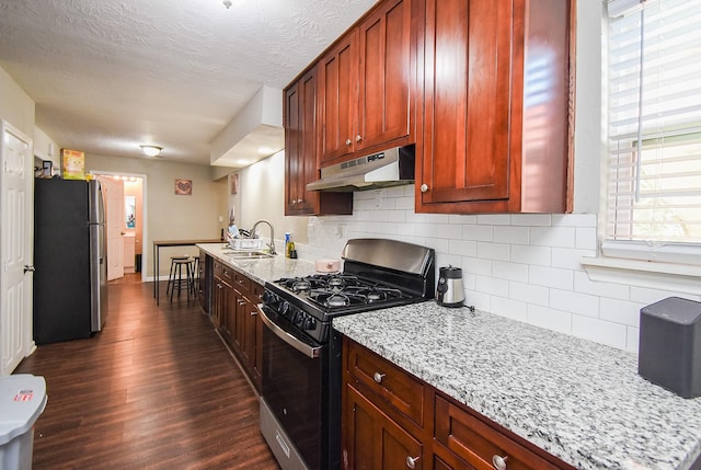 kitchen featuring appliances with stainless steel finishes, dark hardwood / wood-style floors, light stone countertops, and sink