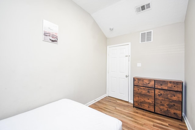 bedroom with lofted ceiling and wood-type flooring