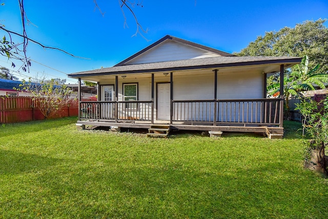 back of property with covered porch and a lawn