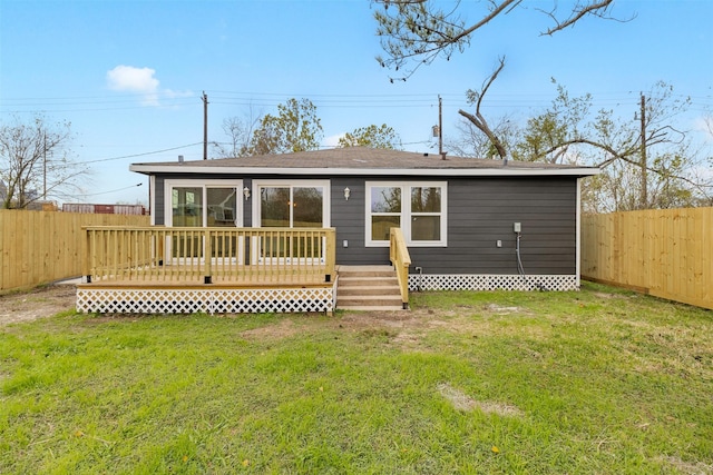 back of house featuring a lawn and a wooden deck