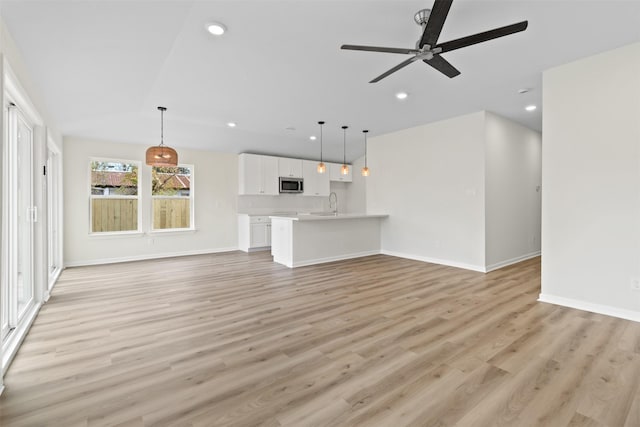 unfurnished living room with ceiling fan, sink, and light hardwood / wood-style floors