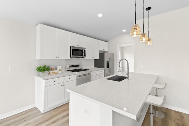 kitchen with appliances with stainless steel finishes, light stone counters, sink, decorative light fixtures, and white cabinetry