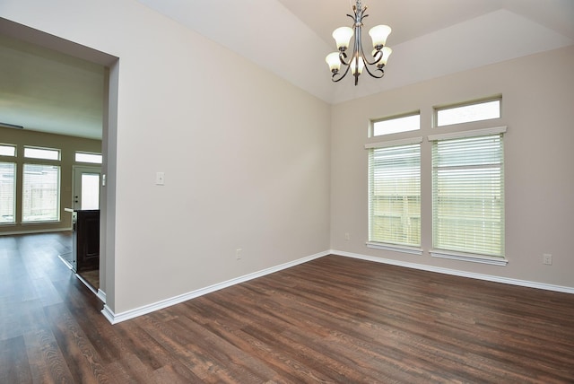 spare room with dark hardwood / wood-style flooring, plenty of natural light, vaulted ceiling, and an inviting chandelier