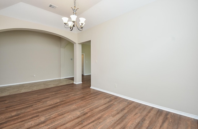 unfurnished room featuring an inviting chandelier and dark wood-type flooring