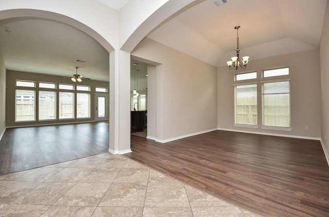 tiled empty room with lofted ceiling and ceiling fan with notable chandelier