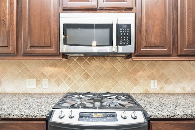 kitchen with tasteful backsplash, light stone counters, and range