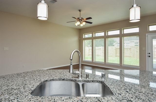 kitchen with light stone countertops, pendant lighting, plenty of natural light, and sink