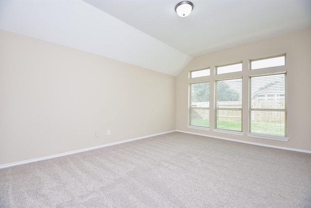 carpeted spare room with vaulted ceiling