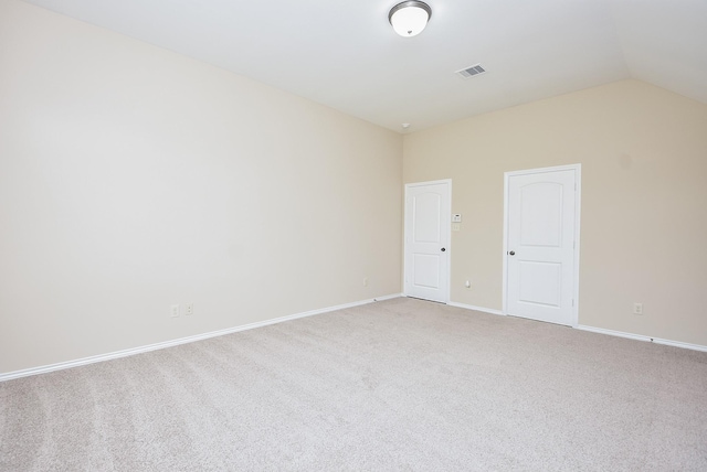 carpeted empty room featuring vaulted ceiling