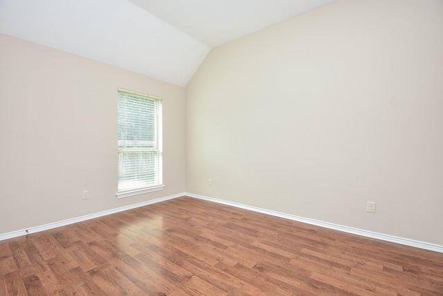 spare room featuring wood-type flooring and lofted ceiling