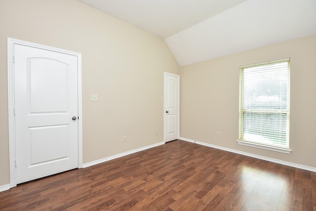 spare room with dark hardwood / wood-style flooring and vaulted ceiling