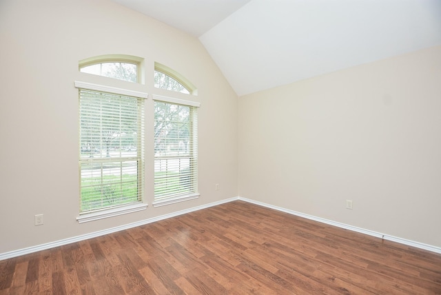 empty room with dark wood-type flooring and vaulted ceiling