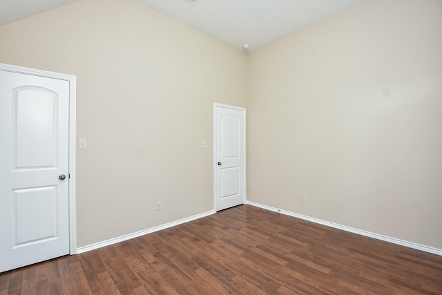 unfurnished room featuring a towering ceiling and dark wood-type flooring