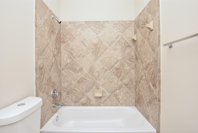 bathroom with toilet and tiled shower / bath