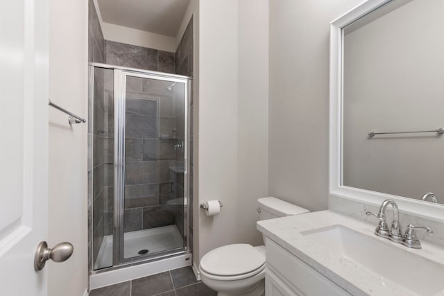 bathroom featuring tile patterned flooring, vanity, toilet, and a shower with shower door