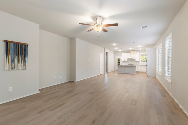 unfurnished living room featuring ceiling fan and light wood-type flooring