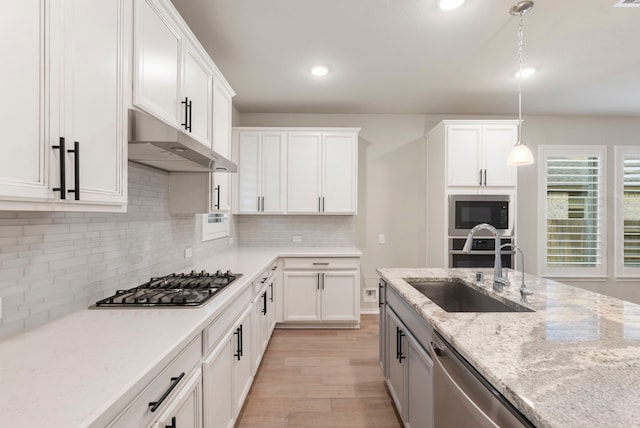 kitchen with decorative backsplash, appliances with stainless steel finishes, sink, decorative light fixtures, and white cabinetry