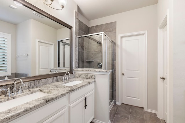 bathroom with a shower with door, vanity, and tile patterned flooring