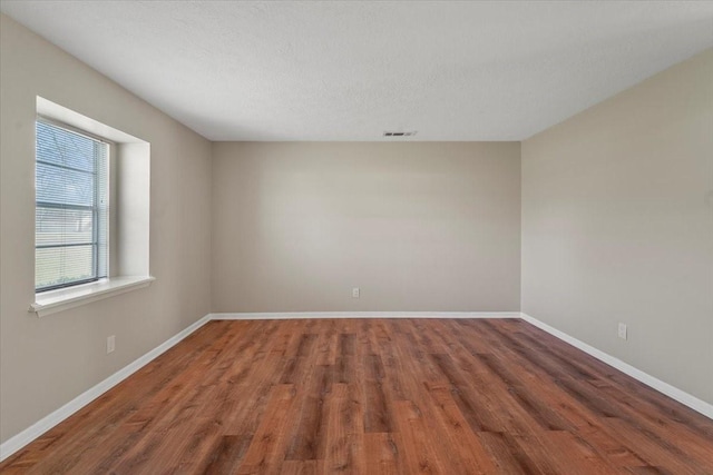 unfurnished room with a textured ceiling and dark wood-type flooring