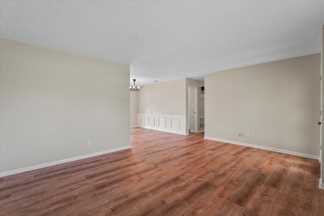 unfurnished room featuring hardwood / wood-style floors, a textured ceiling, and a notable chandelier