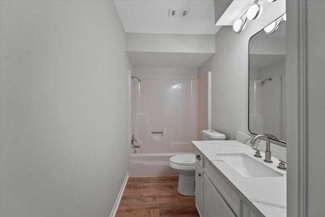 full bathroom with hardwood / wood-style floors, vanity, shower / washtub combination, toilet, and a textured ceiling