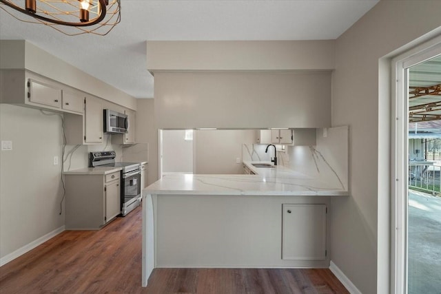 kitchen with kitchen peninsula, appliances with stainless steel finishes, dark wood-type flooring, sink, and white cabinets