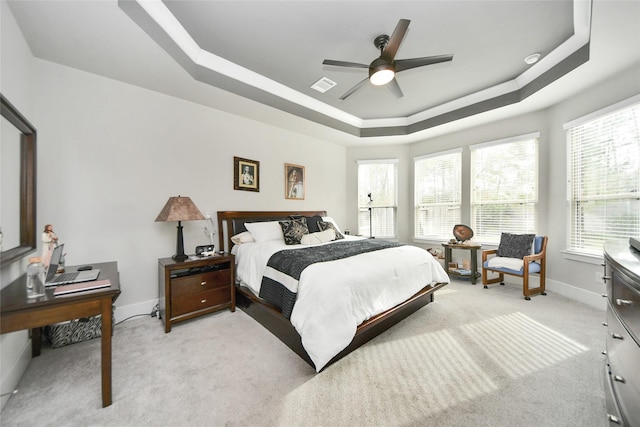 carpeted bedroom featuring ceiling fan and a tray ceiling