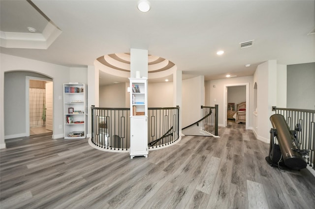 hall with wood-type flooring and a raised ceiling