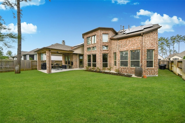 back of property featuring a lawn, central air condition unit, a patio, and solar panels