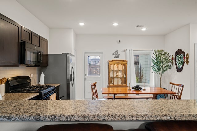 kitchen featuring black appliances, dark brown cabinets, light stone countertops, and tasteful backsplash