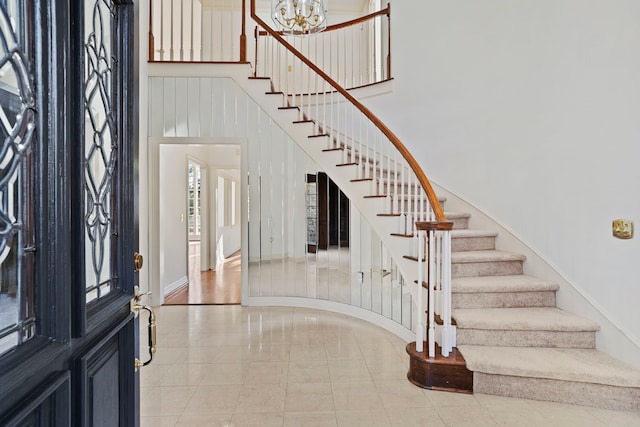 entrance foyer featuring tile patterned flooring, a towering ceiling, and a notable chandelier