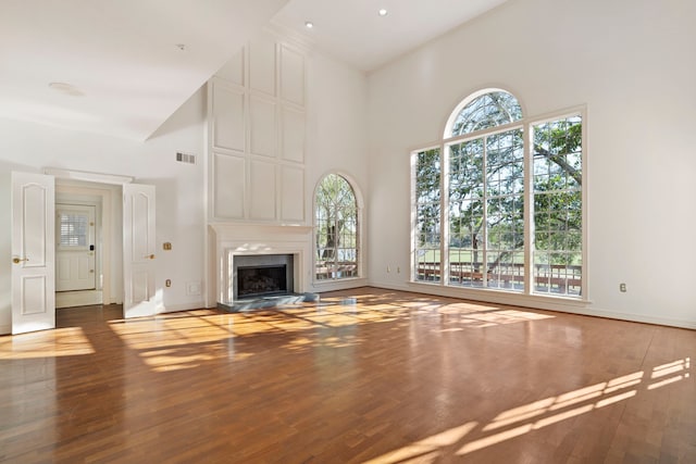 unfurnished living room featuring a fireplace, a high ceiling, and dark hardwood / wood-style floors