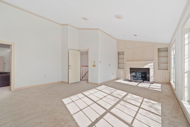 unfurnished living room featuring built in shelves, light colored carpet, a tiled fireplace, and ornamental molding