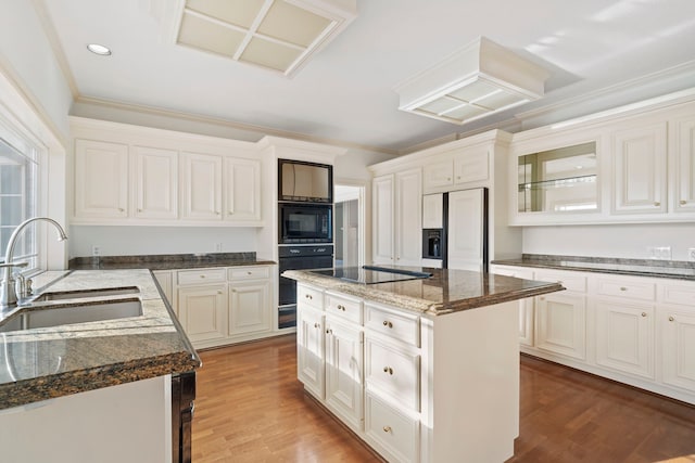 kitchen with black appliances, a kitchen island, sink, and dark stone counters