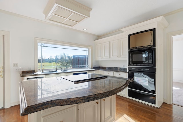 kitchen with a center island, sink, hardwood / wood-style flooring, black appliances, and ornamental molding