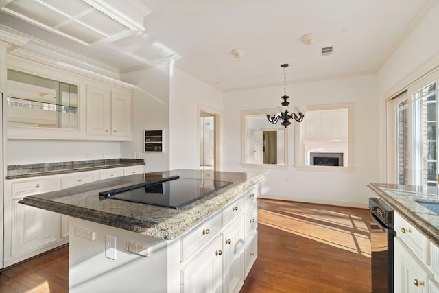 kitchen with dark hardwood / wood-style flooring, black electric cooktop, pendant lighting, an inviting chandelier, and a center island