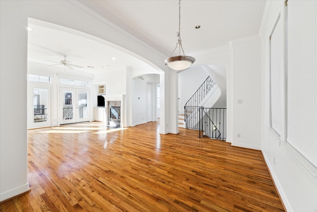 unfurnished living room with ceiling fan, hardwood / wood-style floors, and ornamental molding