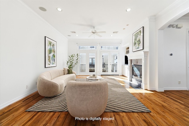 living room with ceiling fan, light hardwood / wood-style flooring, ornamental molding, and a fireplace