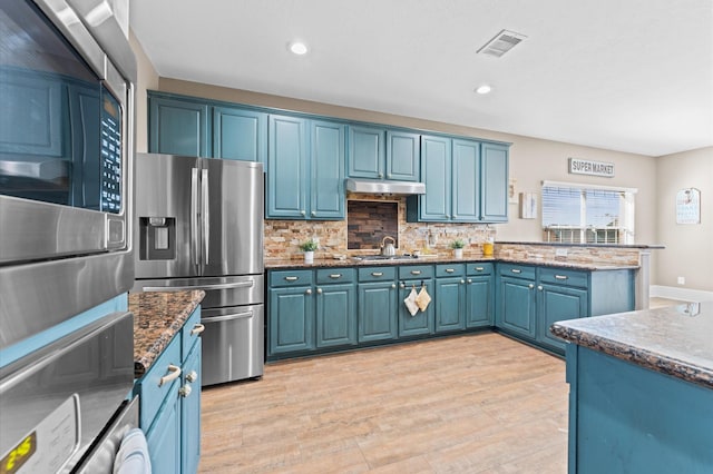 kitchen with blue cabinets, sink, backsplash, stainless steel refrigerator with ice dispenser, and light hardwood / wood-style flooring