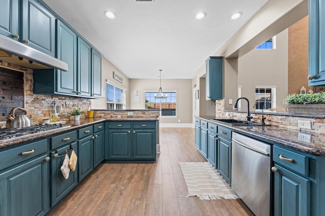 kitchen with decorative light fixtures, stainless steel appliances, kitchen peninsula, and blue cabinets