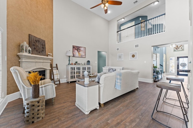 living room with a towering ceiling, ceiling fan with notable chandelier, and dark hardwood / wood-style flooring