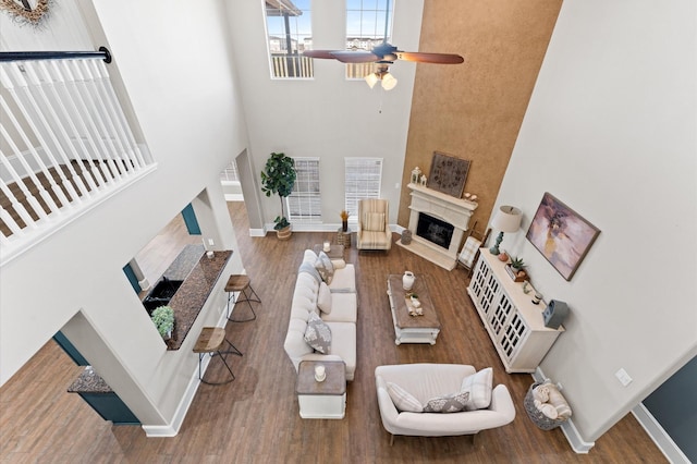 living room with hardwood / wood-style flooring, a towering ceiling, and ceiling fan