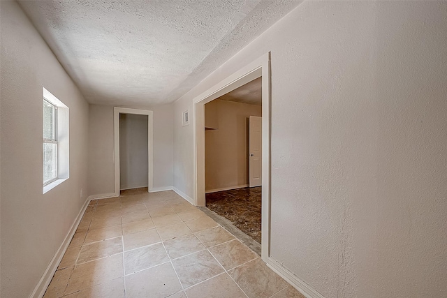 hall featuring light tile patterned flooring and a textured ceiling