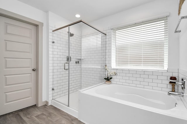 bathroom featuring a healthy amount of sunlight, wood-type flooring, and independent shower and bath