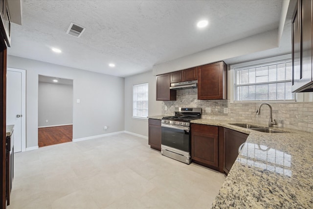 kitchen with backsplash, light stone countertops, sink, and stainless steel range with gas stovetop